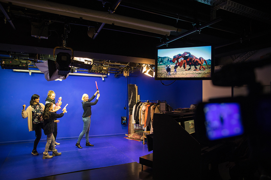 4 Jugendliche stehen in einem blauen Studio mit Scheinwerfer und Kamera