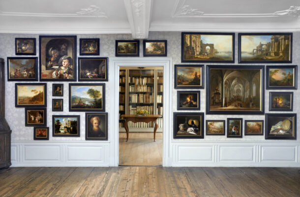 Frontaler Einblick in das Gemäldekabinett des Goethe Hauses. rechts und links hängen verschiedene Gemälde, gerade aus ist ein Zimmer mit verschiedenen Büchern zu sehen.